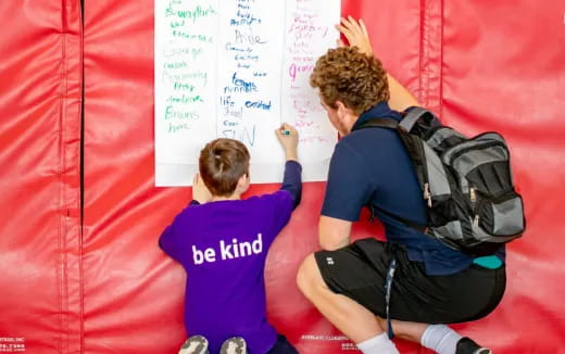 a few boys sitting on a red and white wall