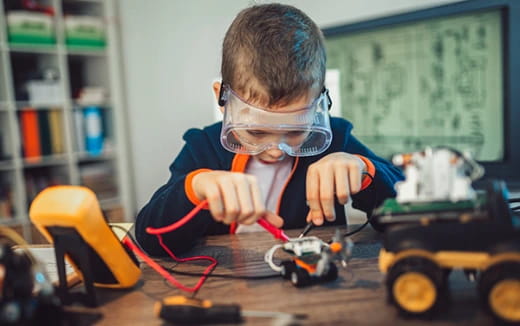 a boy wearing safety goggles and looking at a toy car