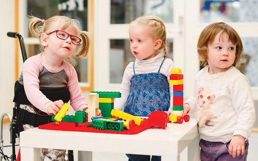a group of children sitting at a table with toys