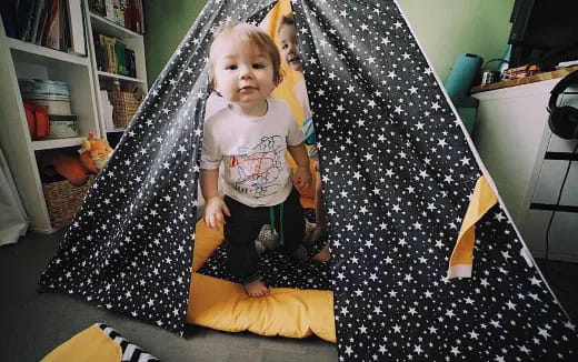 a girl standing next to a bed