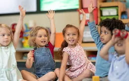 a group of children raising their hands