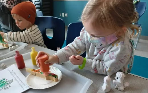 a couple of kids sit at a table eating cake