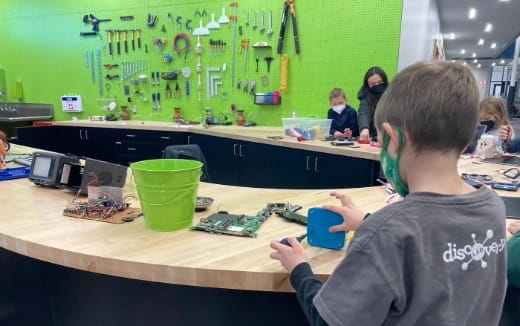 a boy sitting at a desk with a cup and a green cup
