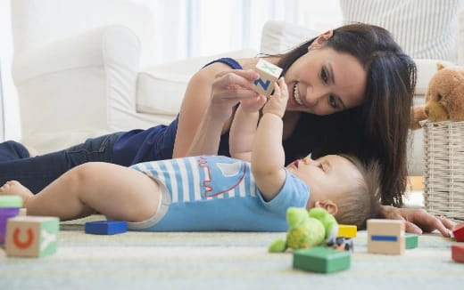 a woman lying on the floor with a baby on her chest