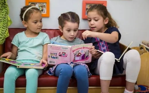 a group of children sitting on a bench reading books