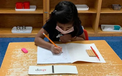 a girl sitting at a table writing on paper