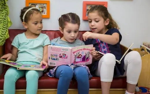 a group of children sitting on a couch reading books