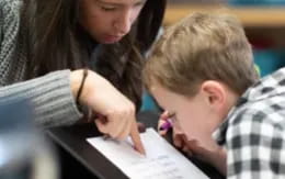 a person and a boy looking at a paper