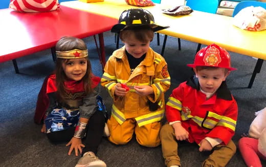 a group of children sitting on the floor wearing hats