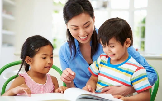 a person and two children looking at a book