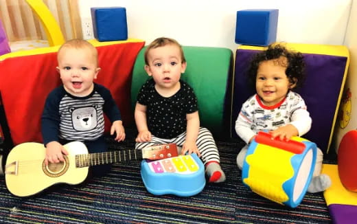 a group of kids sitting on a couch playing a guitar