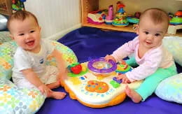 two babies sitting on a blanket