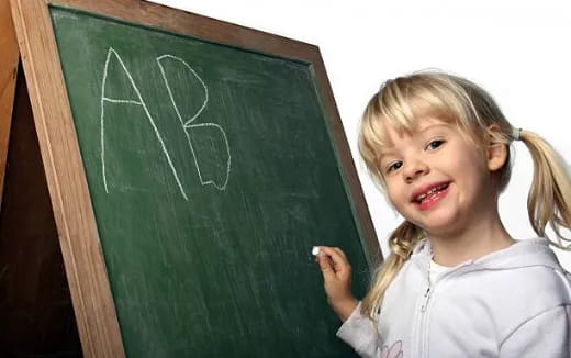a young girl writing on a chalkboard