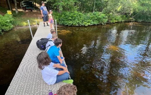 a group of people sitting on a sidewalk next to a river