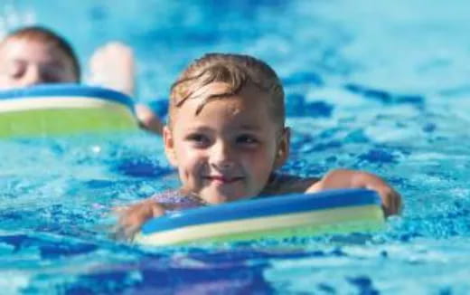 a boy swimming with a surfboard