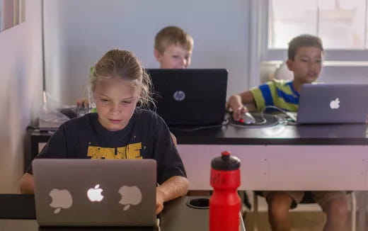 a few kids using laptops