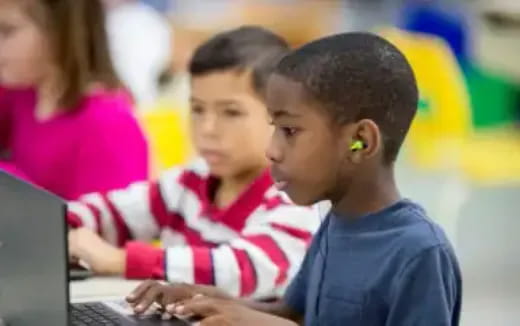 a few young children using laptops
