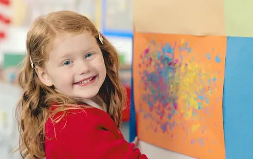 a girl smiling next to a painting