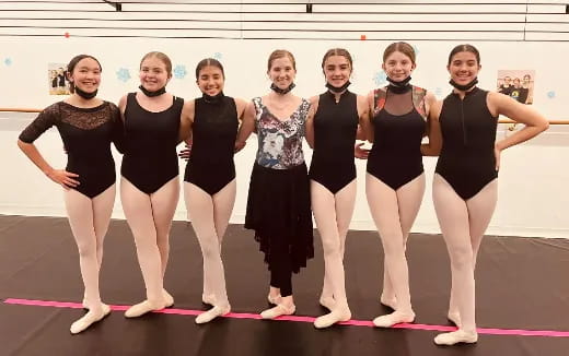 a group of women in black and white leotards posing for a photo