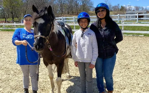 a group of women standing next to a horse
