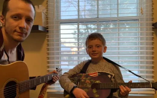 a person and a boy playing guitars