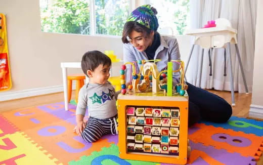 a person and a child playing with toys on a rug