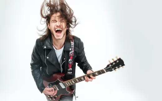 a person with long hair playing a guitar