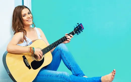 a woman sitting on the floor playing a guitar