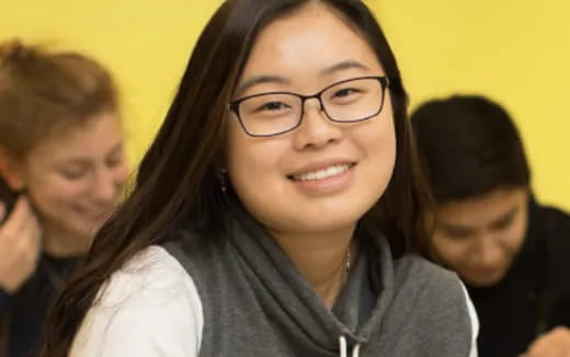 a woman smiling with other people behind her