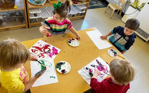 children sitting at a table painting