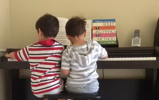 two boys playing piano