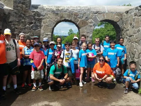 a group of people posing for a photo in front of a stone archway