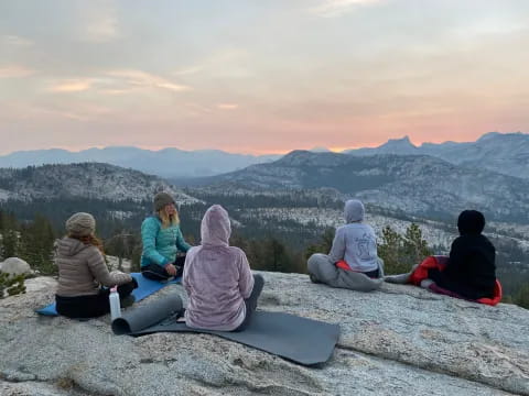 a group of people sitting on a rock overlooking a valley