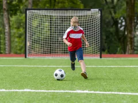 a boy kicking a football ball