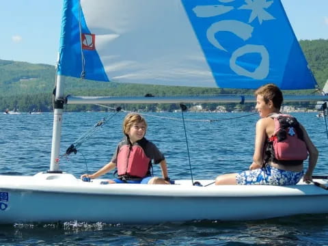 a couple of kids on a sailboat in the water