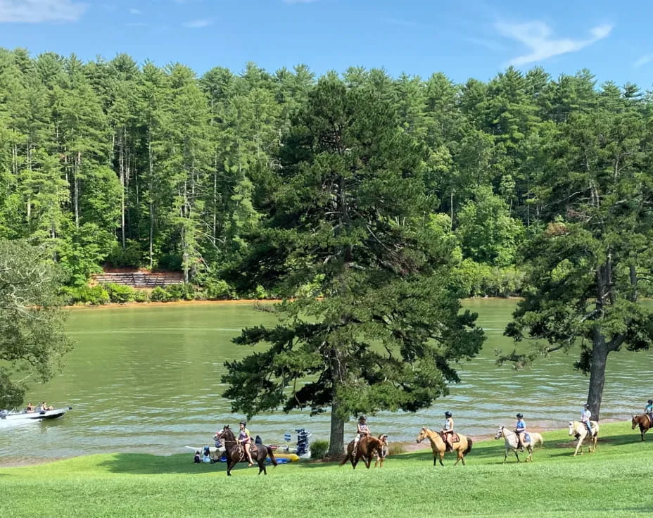 a group of people riding horses by a river