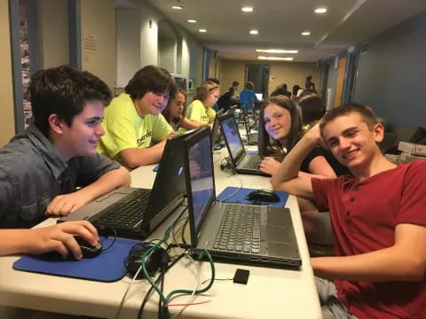 a group of people sitting at a table with laptops