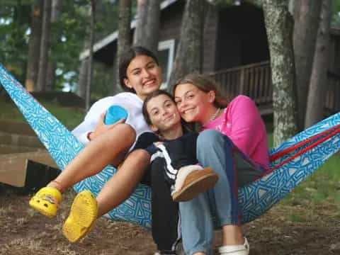 a group of people sitting on a hammock in a park