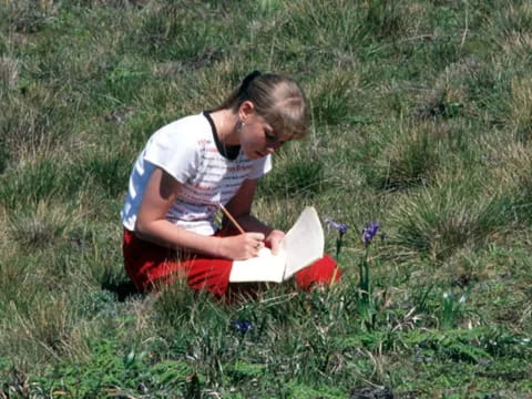 a man sitting in the grass reading a book