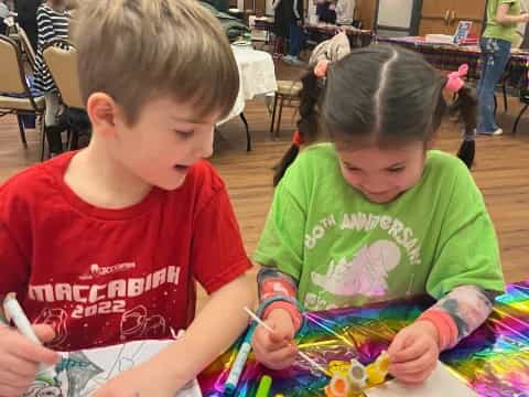 a couple of children sitting at a table looking at a book