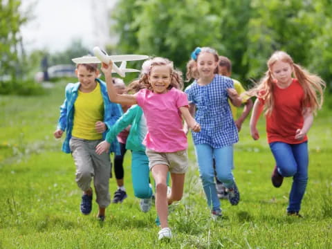 a group of children running in a grassy area