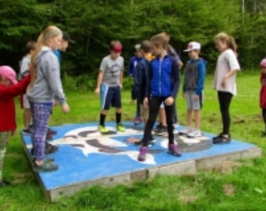 a group of children standing around a pool