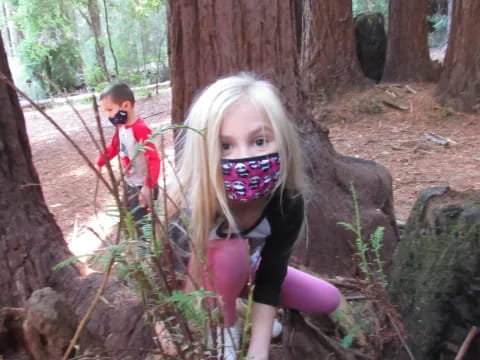 a girl with a face mask and a boy in the background