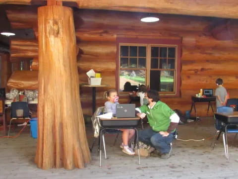 a person and a boy sitting at a table with a laptop