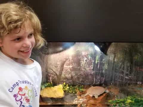 a girl smiling in front of a fish tank