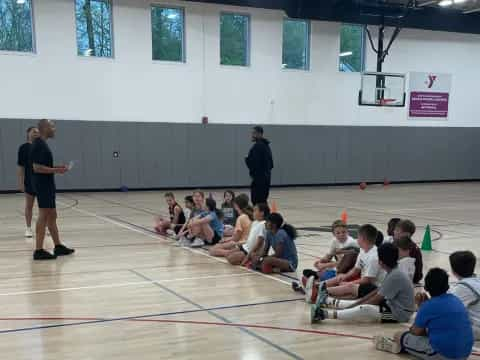 a group of people sitting on the floor in a gym