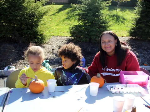 a person and two children sitting at a table outside