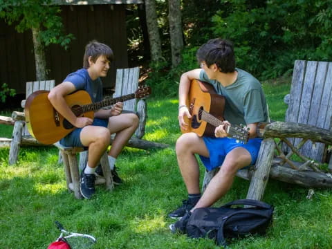 two men sitting on chairs playing guitars