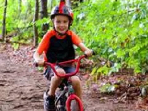 a boy riding a bike on a trail in the woods