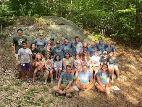 a group of people posing for a photo in front of a large rock